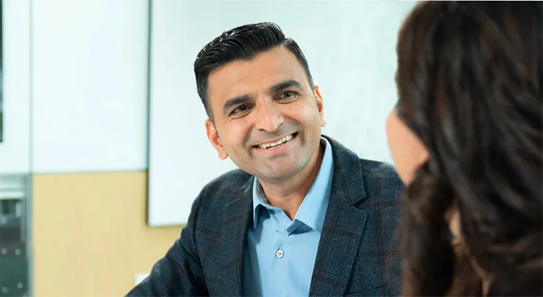 A man smiles at a woman as they talk.